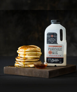 A photo of Bodhi's Gluten Free Pancake Mix and a stack of pancakes.