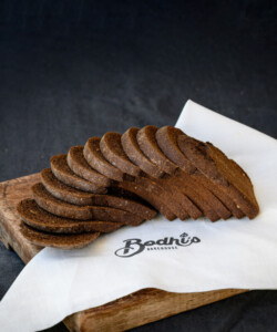 Bodhi's Bakehouse 100% Organic Dark Rye Gourmet in slices on a cutting board.